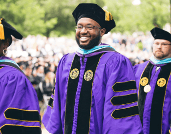 Trevecca graduate stands and smiles at Commencement ceremony.